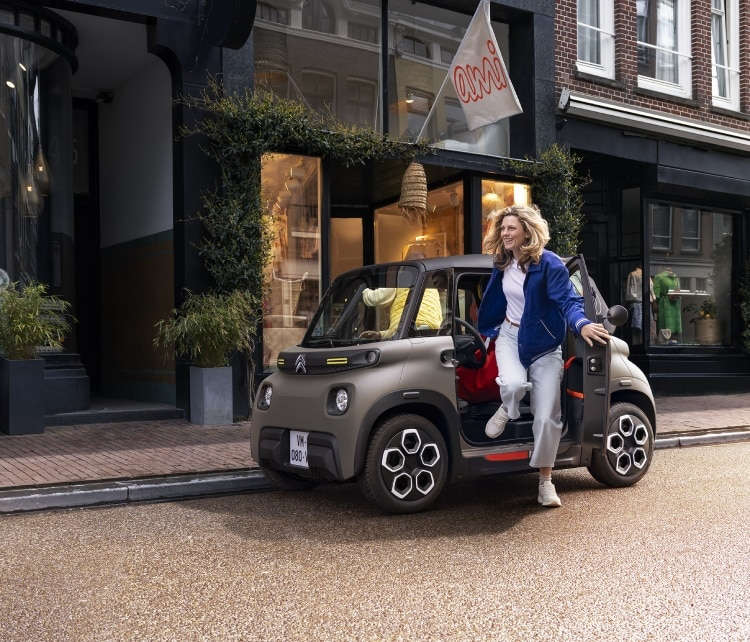 Жінка виходить з Citroën Ami на вулиці